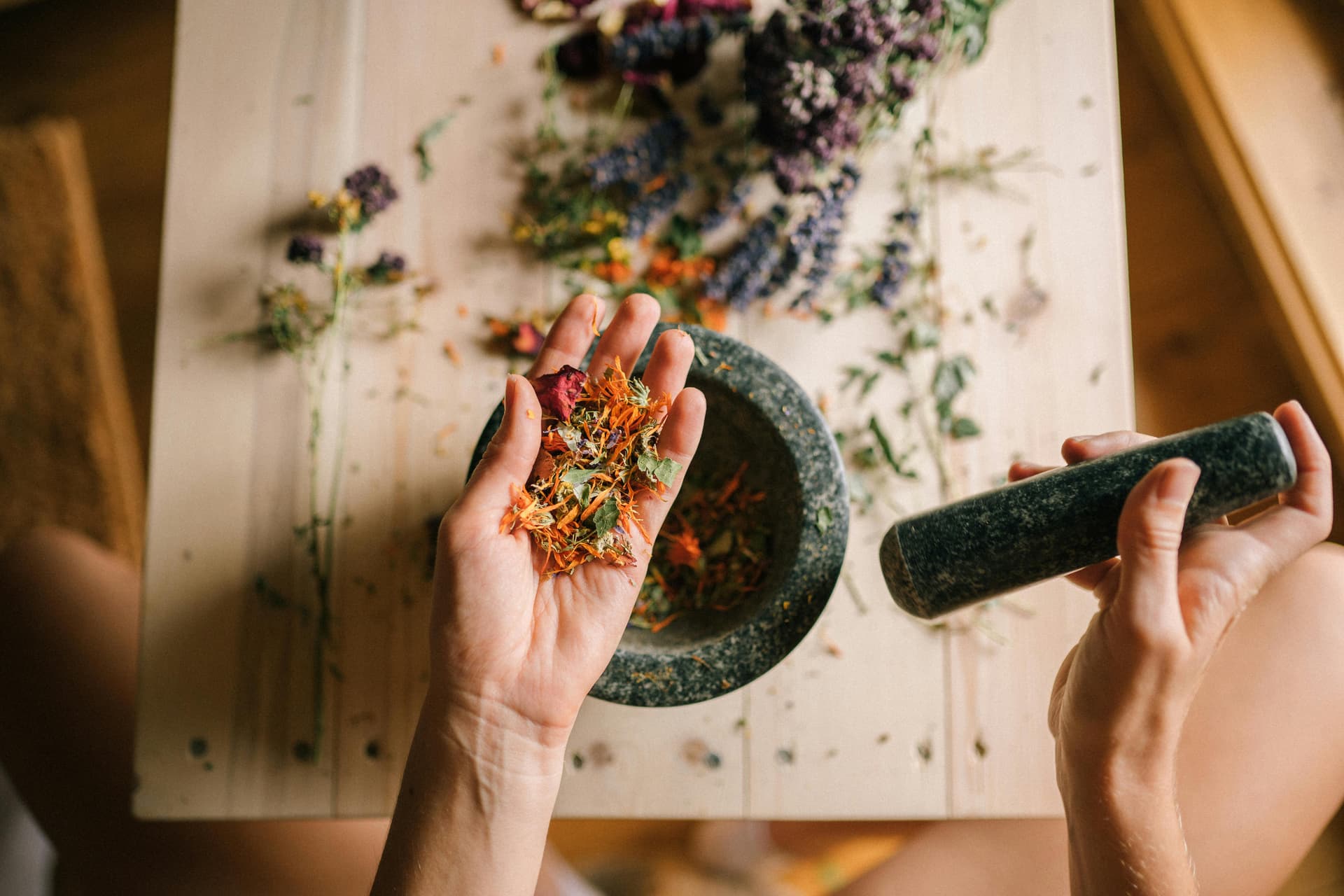 Hands crushing flowers and herbs with a mortar and pestle